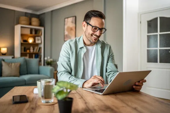 Caucasian man looking at laptop, working online from his home